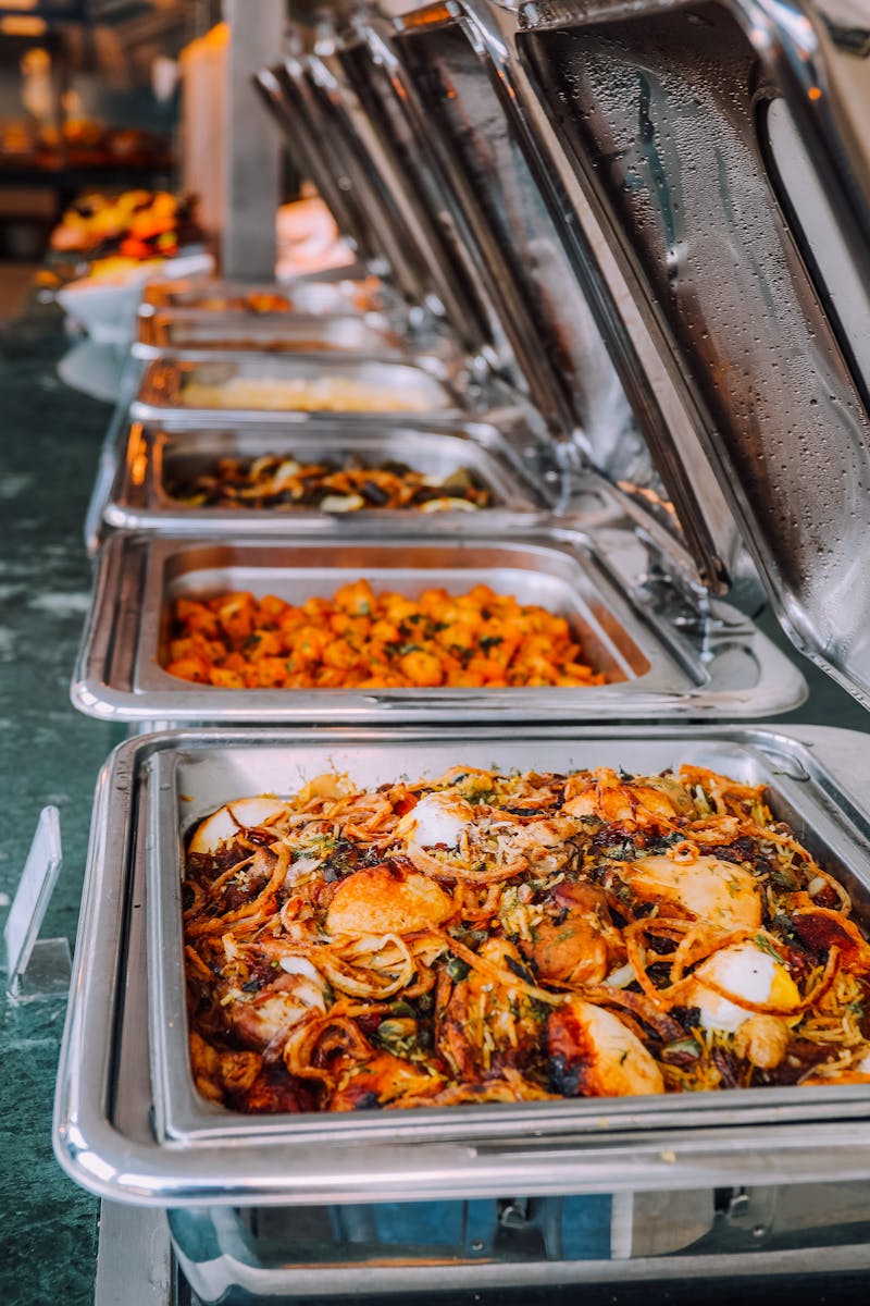 An elegant buffet setup featuring various delicious dishes in stainless steel chafing dishes, perfect for events.